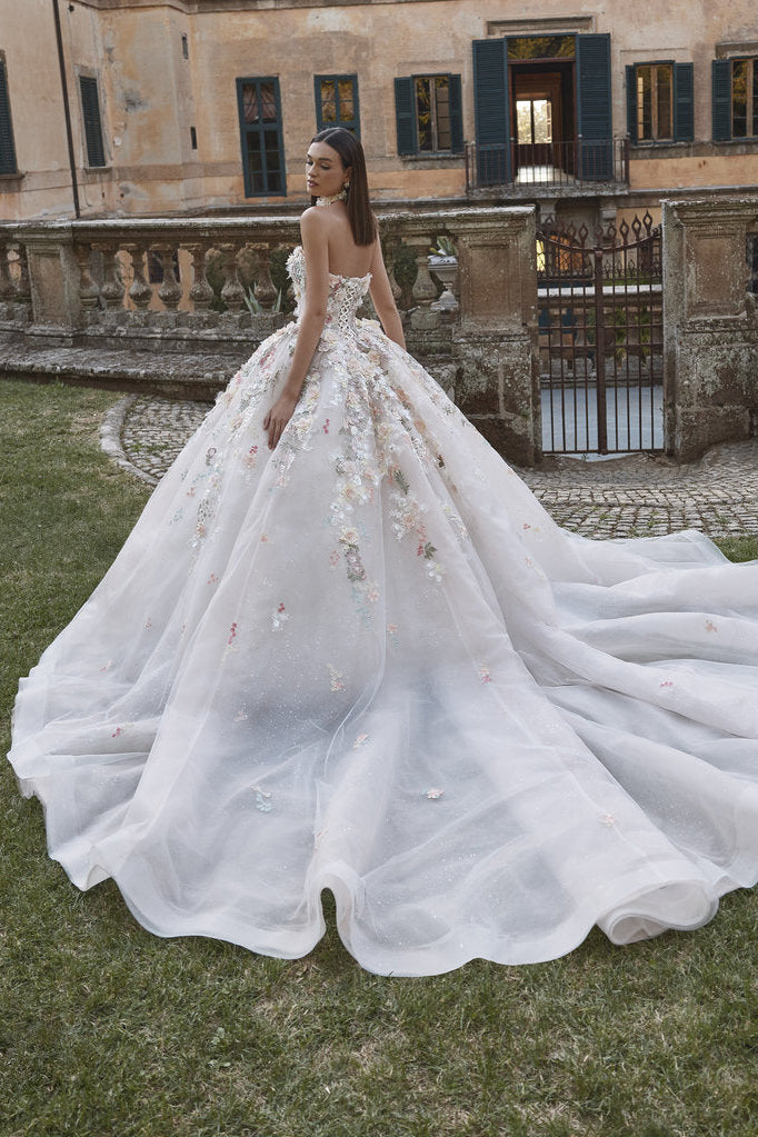 White wedding dress with a long train in front of an old building