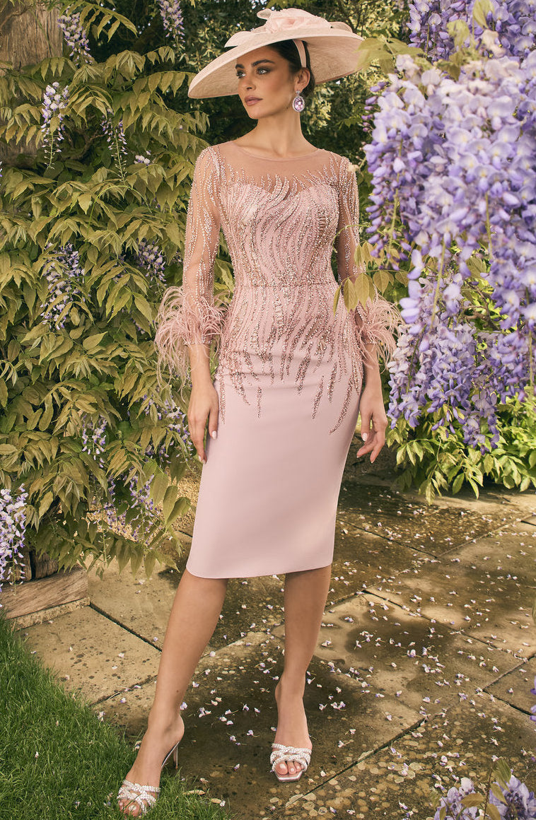 Woman in a pink dress and hat standing in a garden with wisteria